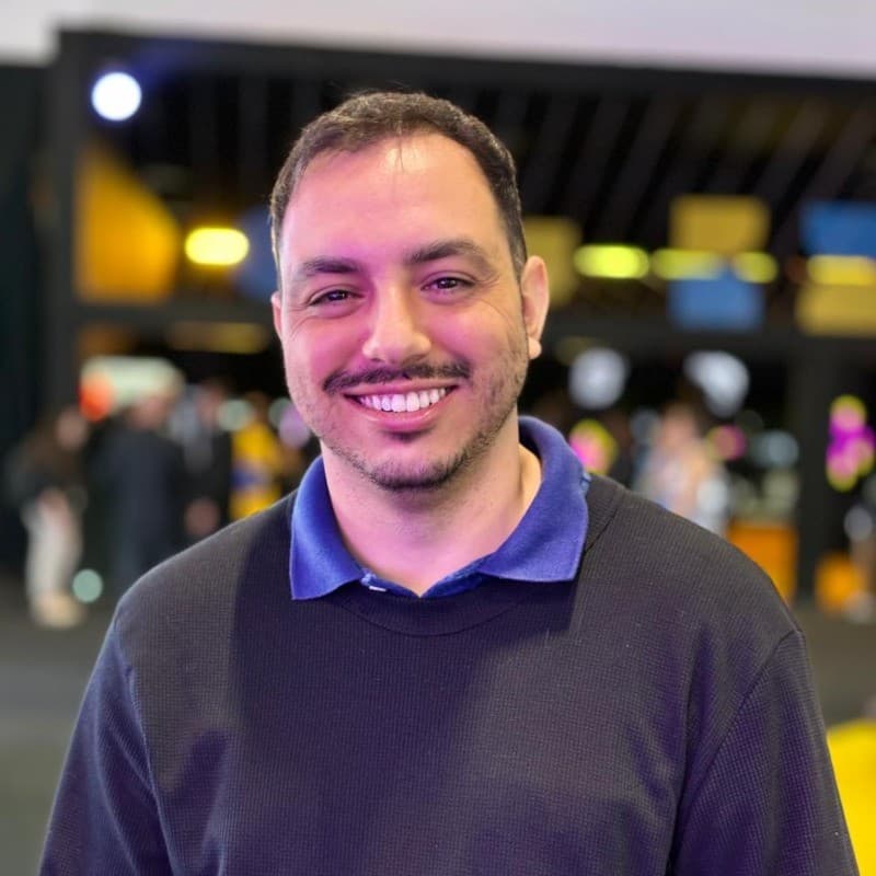 Foto de Marco Antonio, desenvolvedor full-stack, sorrindo em fundo neutro.
